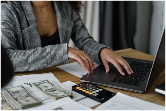 accountant counting cash and checking something on their laptop